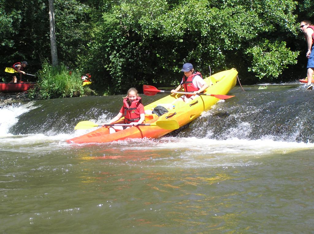 Canoe franchissant un petit barrage sur l'Auvézère en Dordogne.